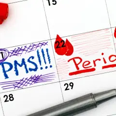 Kalendarz z zaznaczonym PMS i okresem. Dzień 21 oznaczony jako PMS, a dni 22-23 jako okres. Żółty śluz przed okresem to często pierwszy sygnał.