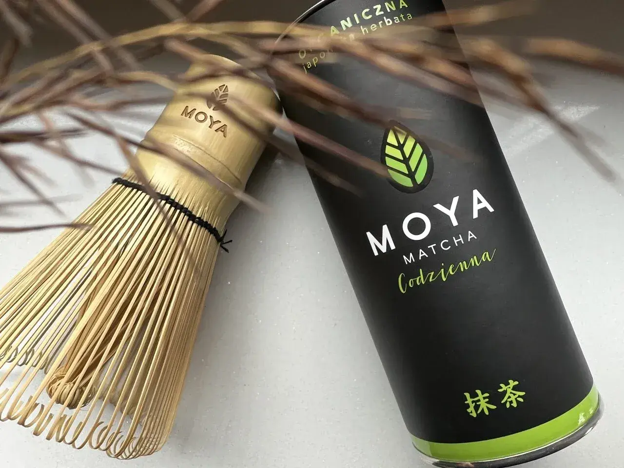 Tradycyjny bambusowy chasen obok puszki MOYA Matcha. Idealny zestaw, by dowiedzieć się, matcha co to jest i jak ją przygotować.